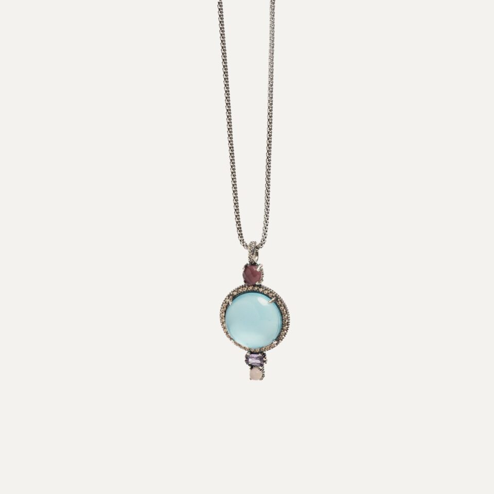 El COLLAR SUNFIELD CL065501 es un collar de plata de ley 925 con cabujón central en aguamarina rodeado de circonitas en color cava, combinado con pequeños cabujones en cuarzo rosa y turmalina. tamaño colgante 2cm. x 3,2cm. largo de la cadena 80cm.